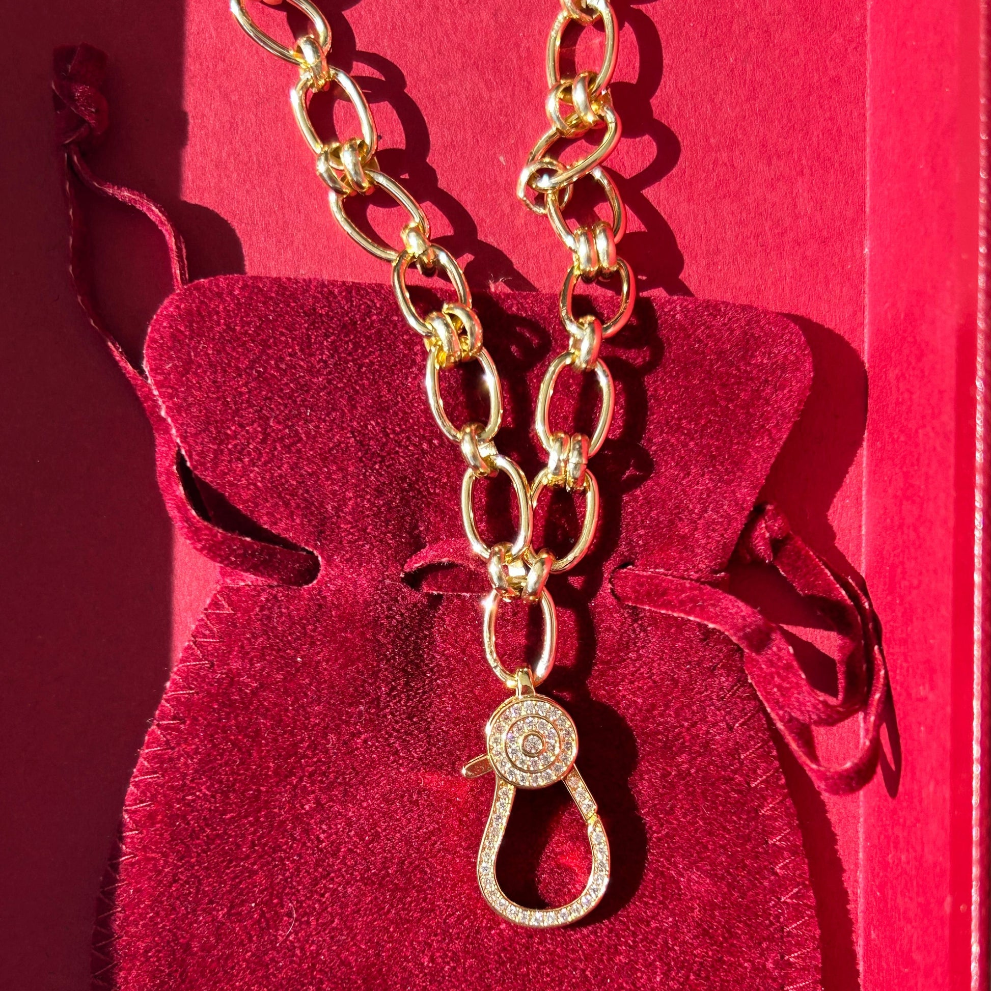 Red heart-shaped pouch with gold chain and clasp on a red background